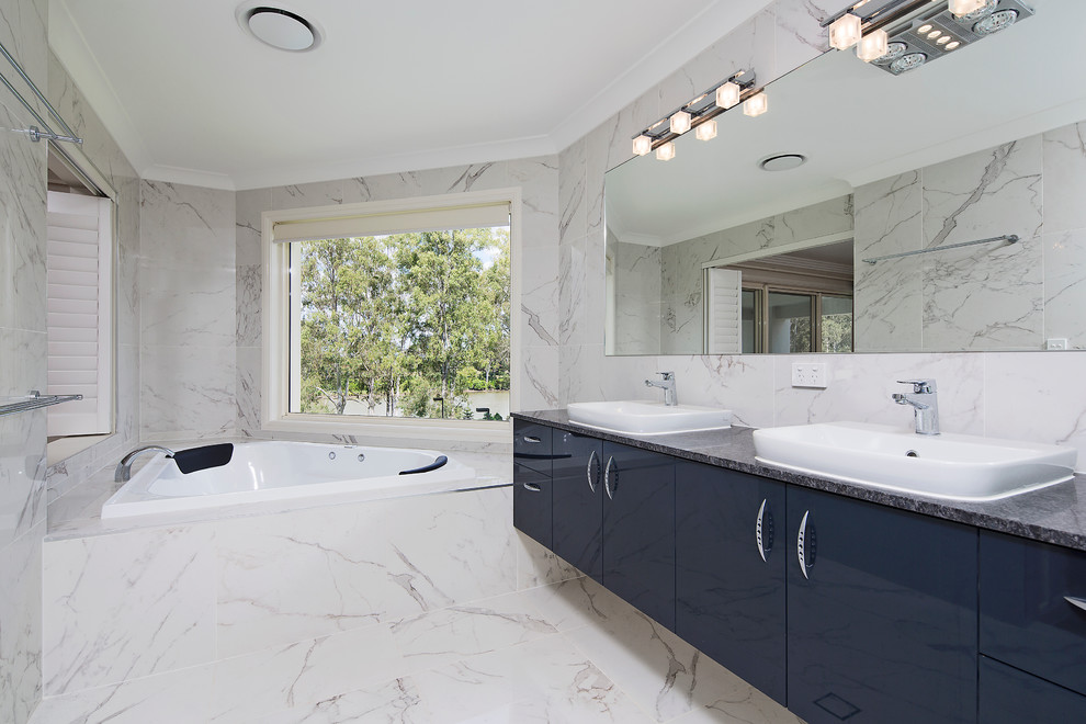 Photo of a contemporary bathroom in Brisbane with flat-panel cabinets, blue cabinets, a drop-in tub, white walls and a vessel sink.