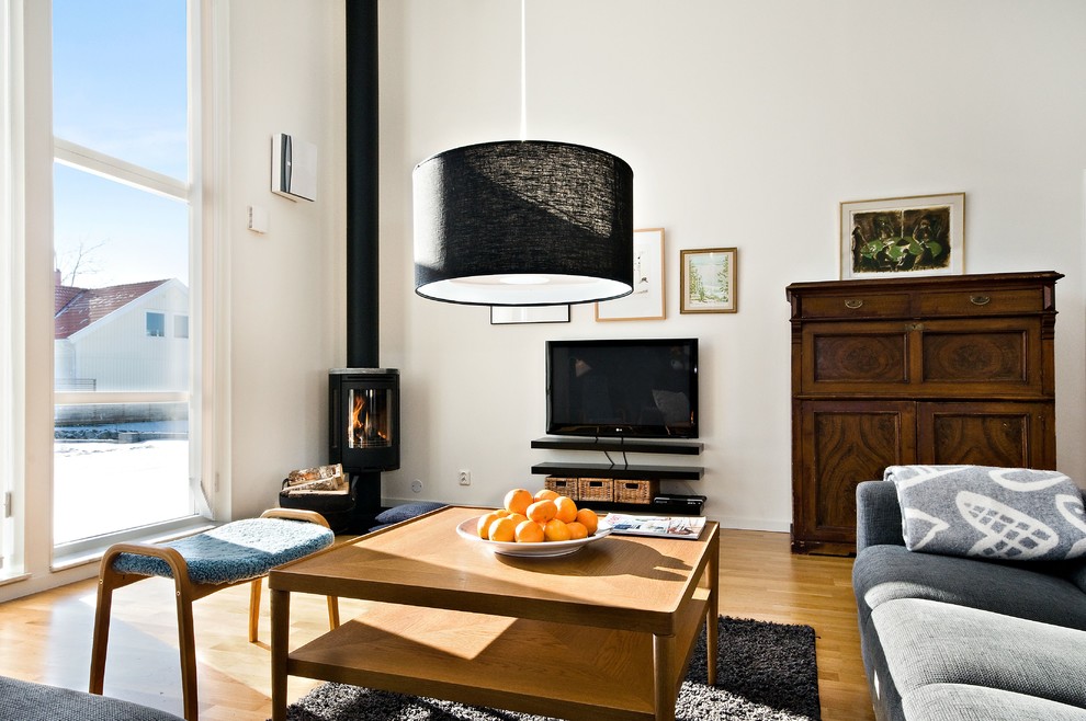 Idéer för ett mellanstort klassiskt allrum med öppen planlösning, med vita väggar, mellanmörkt trägolv, en öppen vedspis, en väggmonterad TV och ett finrum