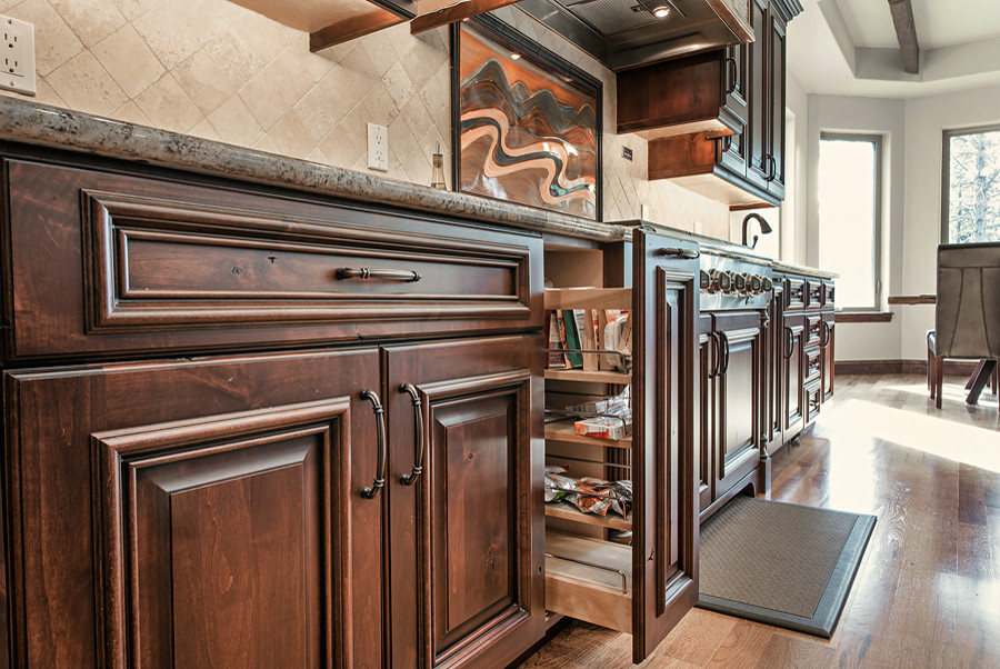 This is an example of a large traditional u-shaped eat-in kitchen in Denver with raised-panel cabinets, brown cabinets, granite benchtops, beige splashback, cement tile splashback, stainless steel appliances, medium hardwood floors and with island.