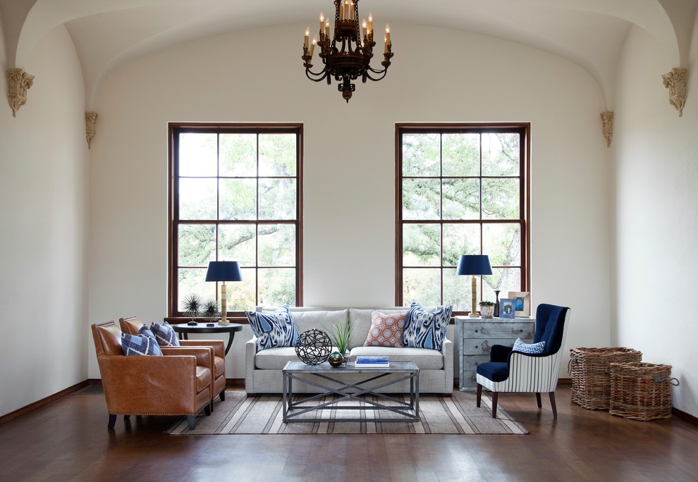 This is an example of a mediterranean formal living room in Austin with white walls and dark hardwood floors.