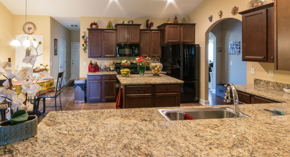 Example of a mid-sized galley cement tile floor and orange floor eat-in kitchen design with an undermount sink, flat-panel cabinets, medium tone wood cabinets, granite countertops, black appliances, an island and beige countertops