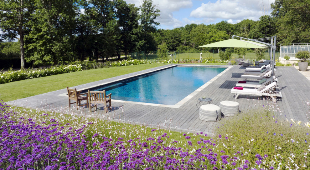 Modelo de piscina natural clásica renovada grande rectangular con paisajismo de piscina y entablado