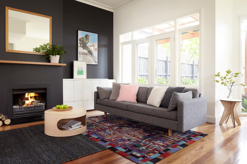 Inspiration for a contemporary living room in Melbourne with black walls, medium hardwood floors and a standard fireplace.