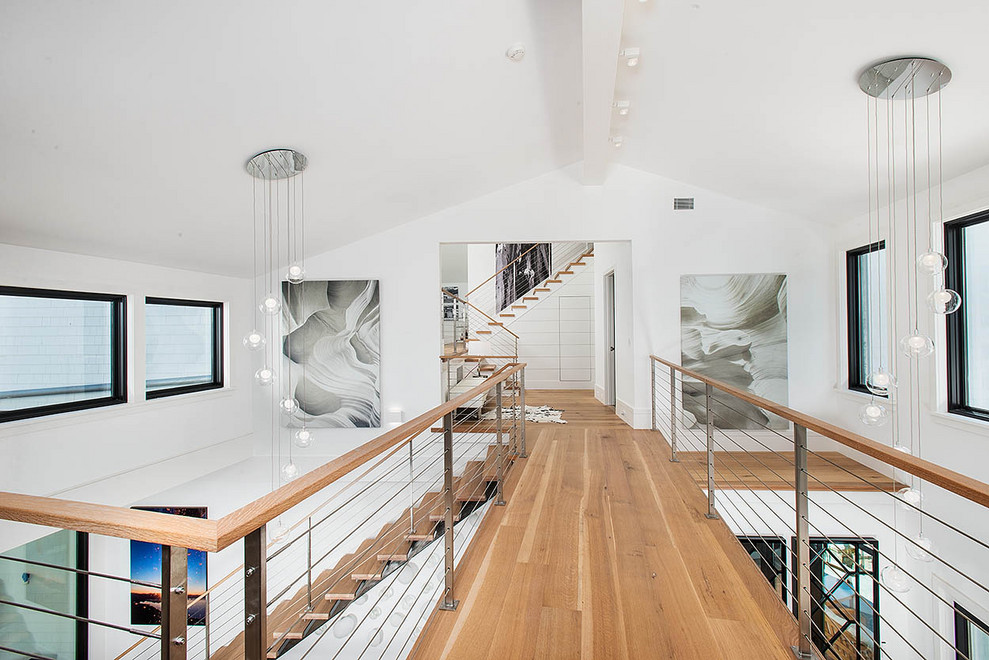 This is an example of a country hallway in New York with white walls, light hardwood floors and vaulted.