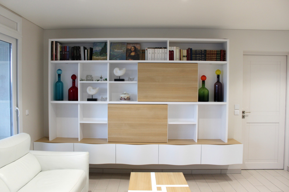 Cette image montre un salon design avec une bibliothèque ou un coin lecture, un mur beige, un sol en carrelage de céramique, un téléviseur encastré et un sol beige.