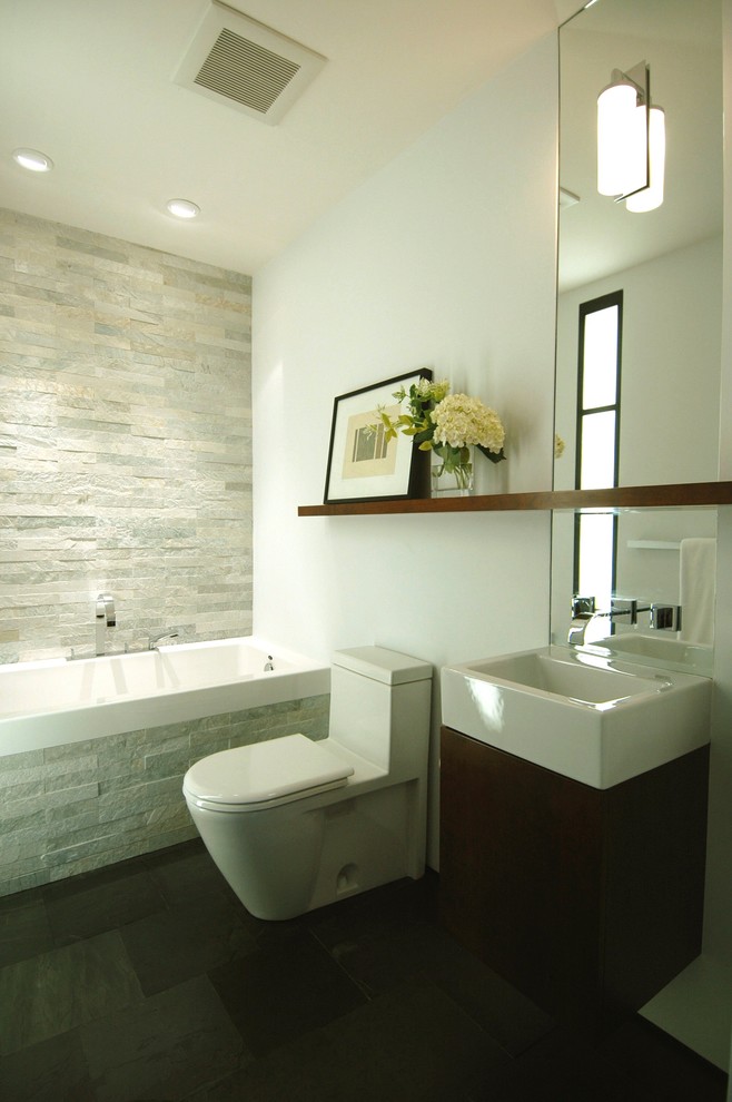 Small contemporary 3/4 bathroom in San Francisco with an integrated sink, an alcove tub, stone tile, flat-panel cabinets, dark wood cabinets, a shower/bathtub combo, a one-piece toilet, white walls, slate floors and gray tile.