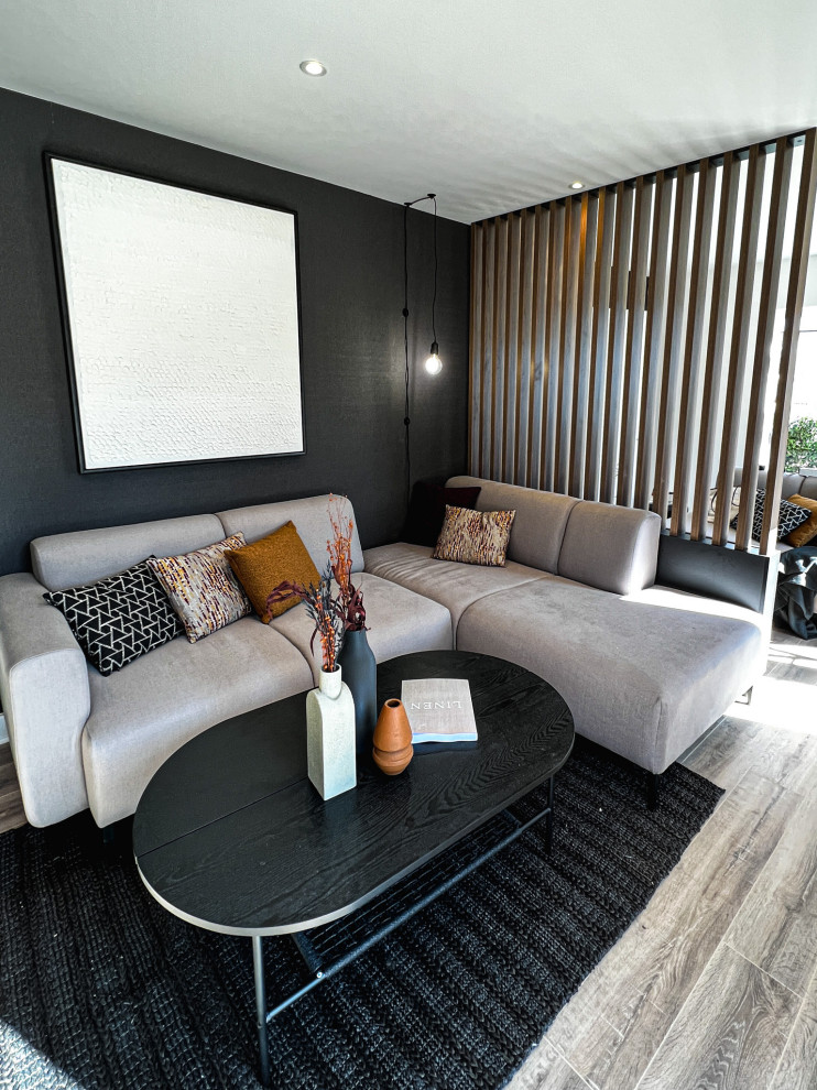 This is an example of a large scandi living room feature wall in West Midlands with beige walls, laminate floors, a wall mounted tv and wallpapered walls.