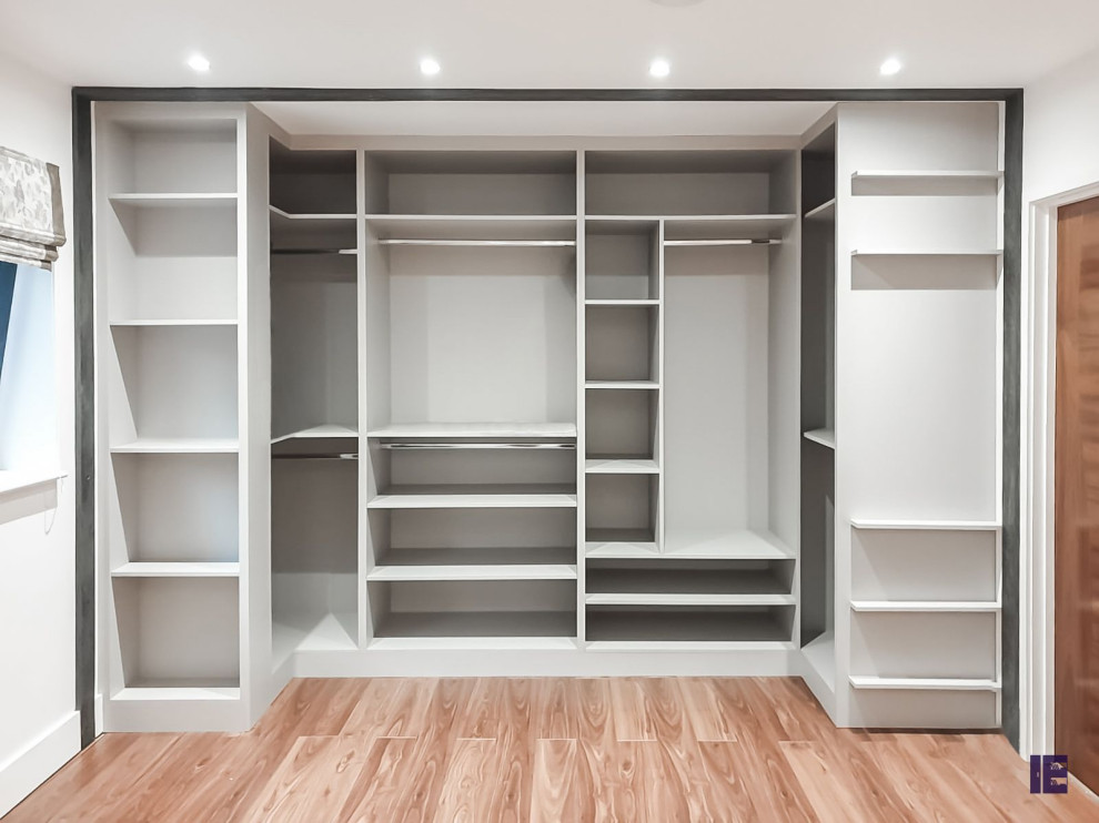 Design ideas for a large modern walk-in wardrobe in London with glass-front cabinets and white cabinets.