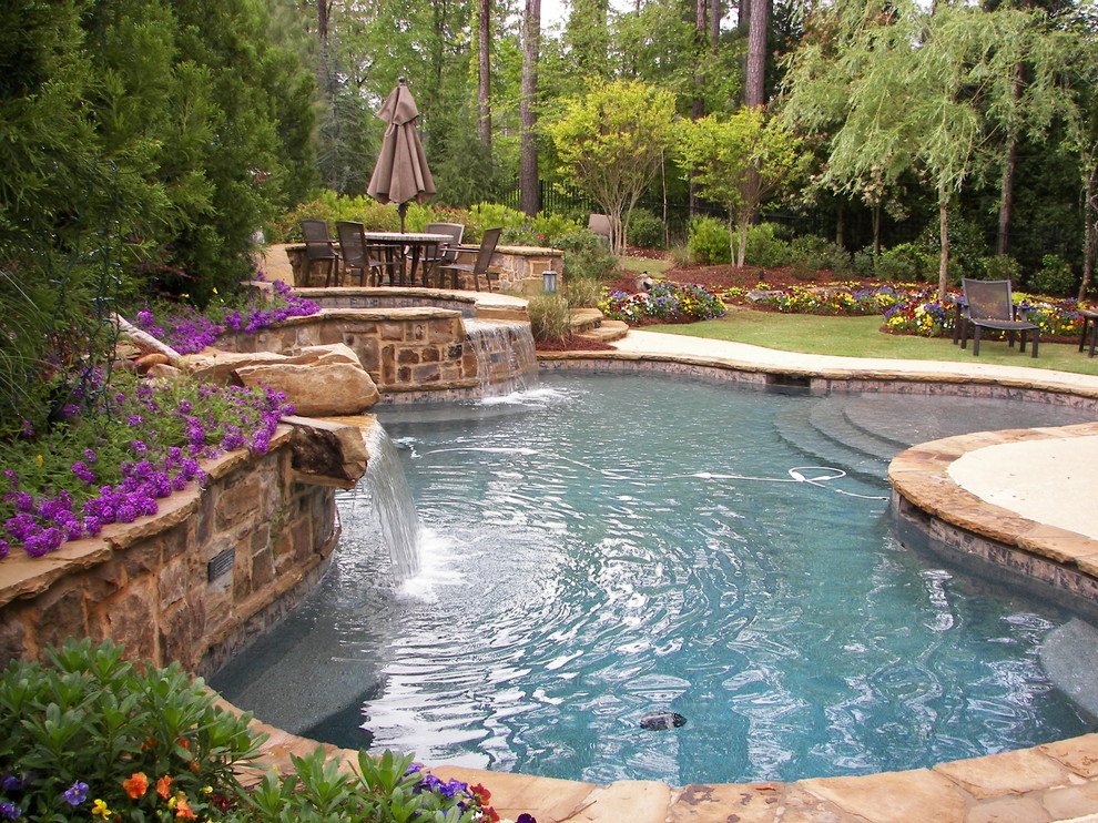 Photo of a large traditional backyard custom-shaped lap pool in Atlanta with a hot tub and natural stone pavers.