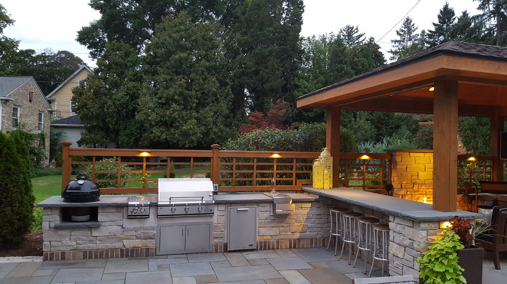 Photo of a large traditional backyard patio in Milwaukee with an outdoor kitchen, natural stone pavers and a gazebo/cabana.