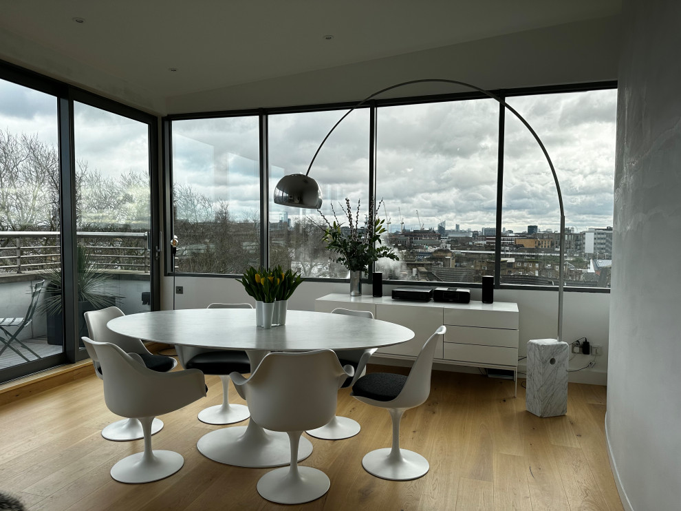 This is an example of a medium sized contemporary open plan dining room in London with white walls and medium hardwood flooring.