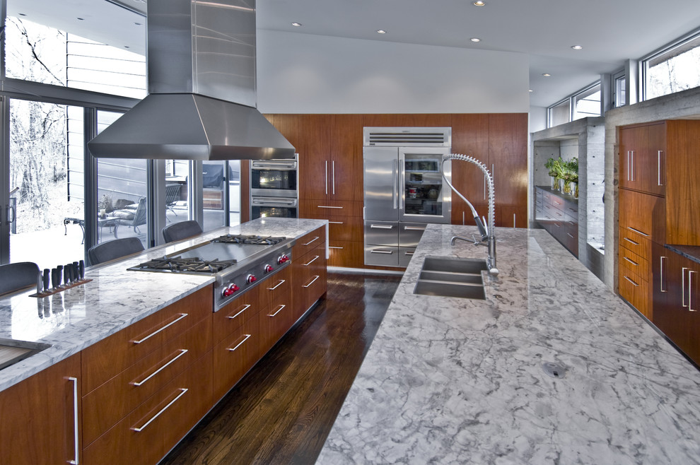 Inspiration for a large modern l-shaped separate kitchen in Other with a triple-bowl sink, flat-panel cabinets, medium wood cabinets, granite benchtops, grey splashback, cement tile splashback, stainless steel appliances, dark hardwood floors and multiple islands.