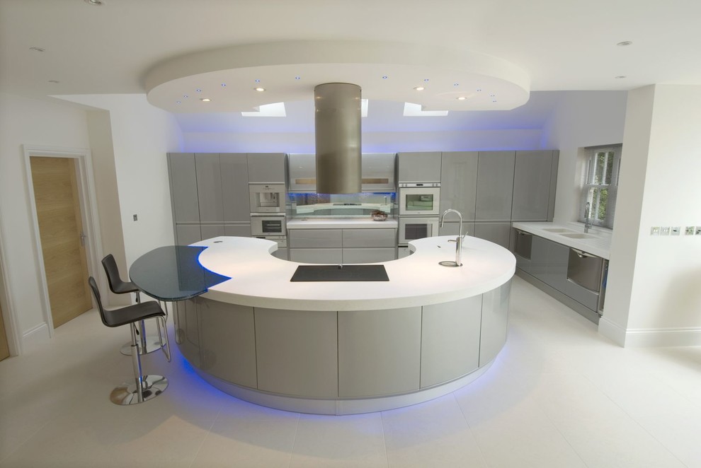 Photo of an expansive modern u-shaped eat-in kitchen in London with an integrated sink, flat-panel cabinets, grey cabinets, solid surface benchtops, multi-coloured splashback, glass sheet splashback, stainless steel appliances, porcelain floors and with island.