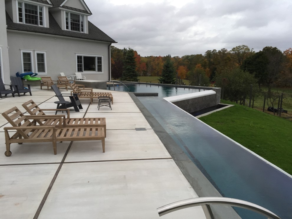 Photo of a large country backyard l-shaped lap pool in New York with concrete slab.