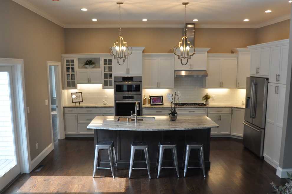 Inspiration for a large transitional l-shaped open plan kitchen in Boston with an undermount sink, flat-panel cabinets, white cabinets, quartzite benchtops, white splashback, ceramic splashback, stainless steel appliances, dark hardwood floors, with island and brown floor.