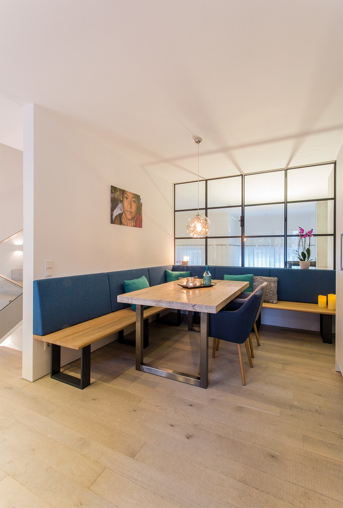 This is an example of a mid-sized industrial open plan dining in Hamburg with white walls, light hardwood floors, no fireplace and beige floor.