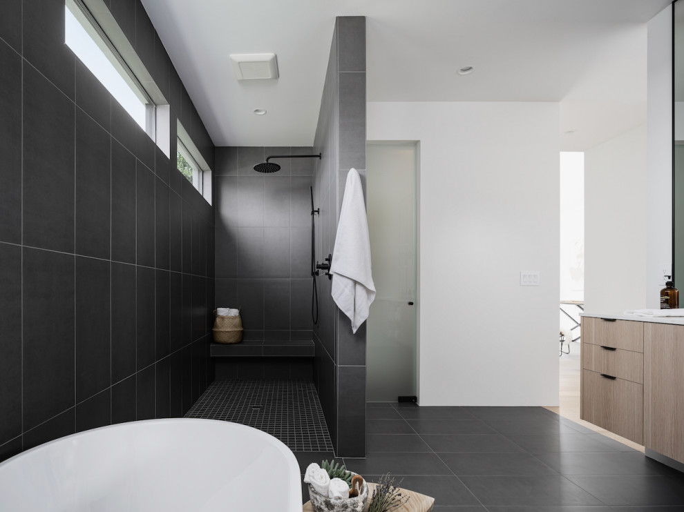 This is an example of a medium sized scandinavian ensuite bathroom in Phoenix with flat-panel cabinets, light wood cabinets, a freestanding bath, a built-in shower, grey tiles, porcelain tiles, white walls, porcelain flooring, a built-in sink, engineered stone worktops, grey floors, an open shower, white worktops, an enclosed toilet, double sinks and a floating vanity unit.