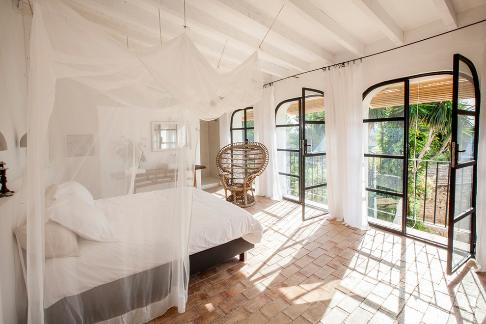 На фото: хозяйская спальня в средиземноморском стиле с белыми стенами и полом из терракотовой плитки с
