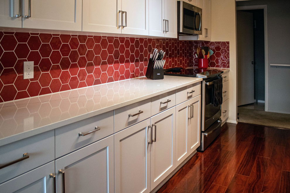 Inspiration for a small transitional galley eat-in kitchen in Cleveland with flat-panel cabinets, white cabinets, quartz benchtops, red splashback, porcelain splashback, stainless steel appliances, no island and white benchtop.