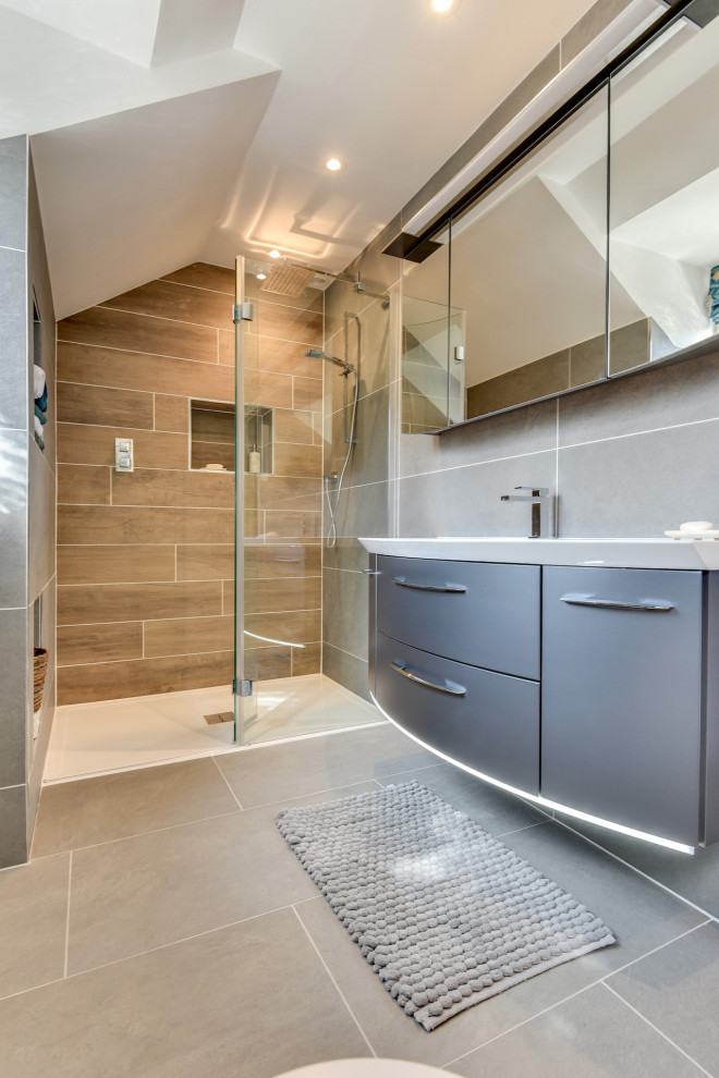 Large minimalist master gray tile and ceramic tile ceramic tile, gray floor and single-sink bathroom photo in Sussex with flat-panel cabinets, gray cabinets, a one-piece toilet, gray walls, a drop-in sink, glass countertops, white countertops and a floating vanity