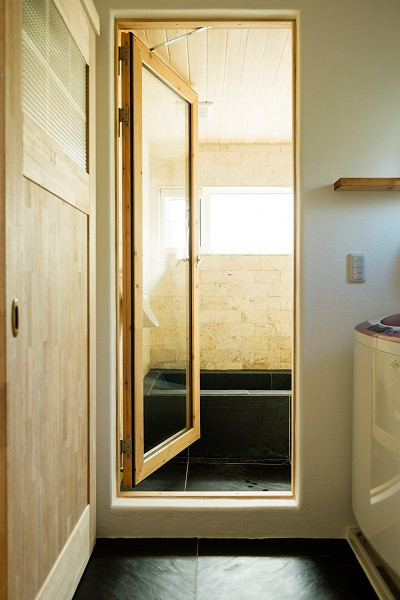 神戸にある北欧スタイルのおしゃれなマスターバスルーム (ベージュのタイル、ライムストーンタイル、開き戸のシャワー、板張り天井) の写真