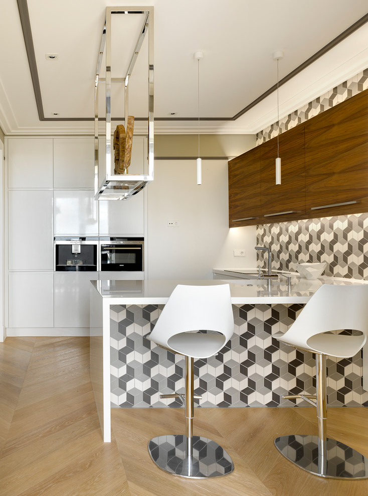Design ideas for a contemporary u-shaped open plan kitchen in Moscow with flat-panel cabinets, white cabinets, multi-coloured splashback, light hardwood floors, a peninsula, an integrated sink, solid surface benchtops, ceramic splashback and black appliances.