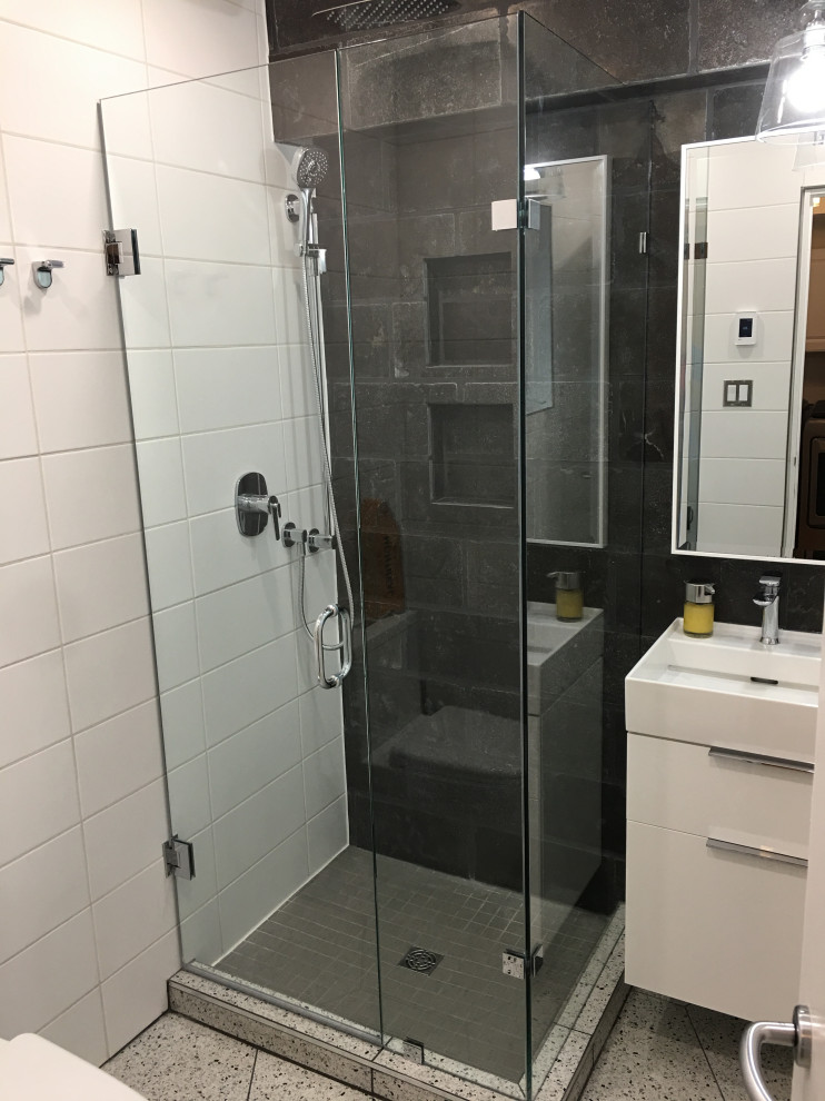 Photo of a small modern master bathroom in Toronto with flat-panel cabinets, white cabinets, a corner shower, a one-piece toilet, black and white tile, stone tile, white walls, porcelain floors, an integrated sink, tile benchtops, a hinged shower door, white benchtops, a single vanity and a floating vanity.