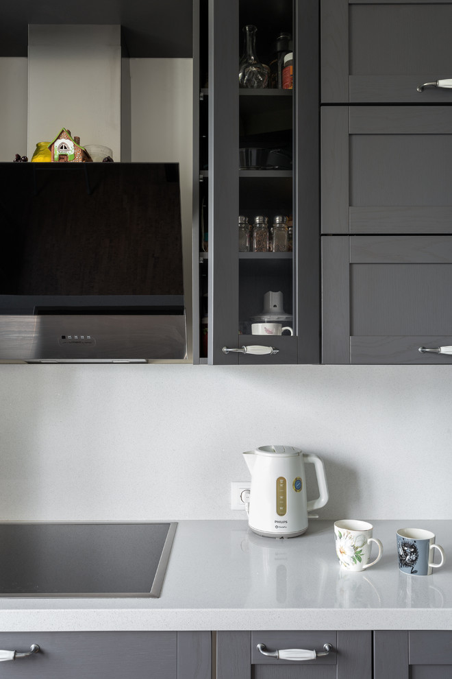 This is an example of a mid-sized scandinavian l-shaped separate kitchen in Moscow with a drop-in sink, shaker cabinets, grey cabinets, quartz benchtops, white splashback, stone slab splashback, black appliances, cork floors, no island, brown floor and white benchtop.