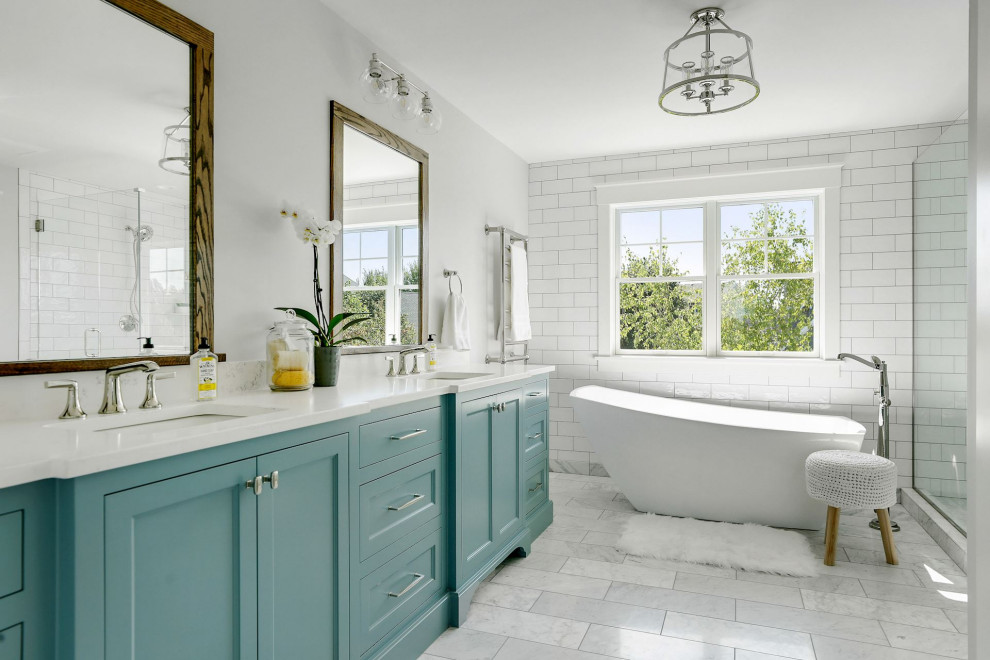 Design ideas for a beach style master bathroom in Minneapolis with shaker cabinets, blue cabinets, a freestanding tub, white tile, subway tile, grey walls, an undermount sink, grey floor, white benchtops, a double vanity and a built-in vanity.