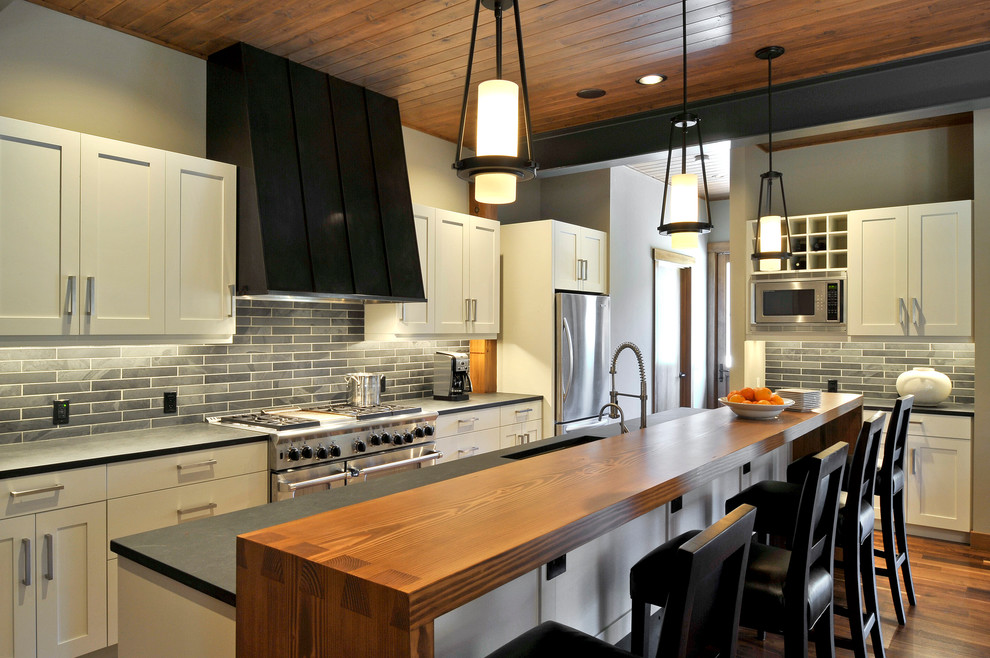 Design ideas for a transitional l-shaped kitchen in Seattle with stainless steel appliances, wood benchtops, black splashback, with island, a single-bowl sink and dark hardwood floors.