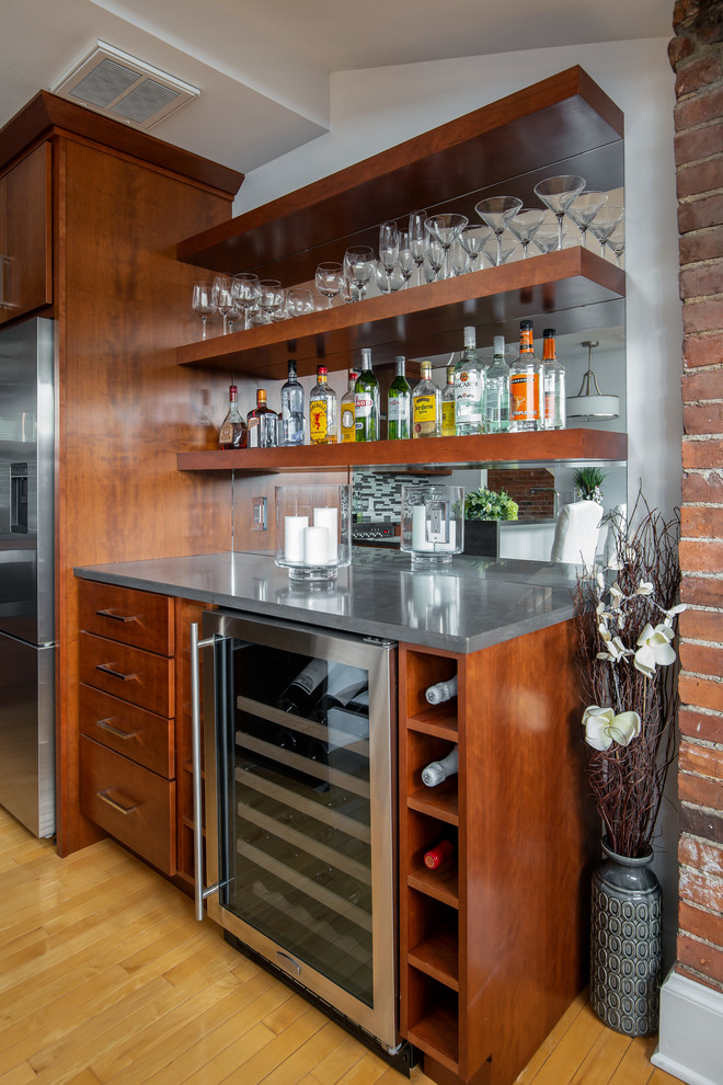 Inspiration for a mid-sized contemporary single-wall light wood floor and beige floor wet bar remodel in Boston with flat-panel cabinets, medium tone wood cabinets, quartz countertops, stainless steel appliances, a peninsula, gray countertops, no sink and mirror backsplash