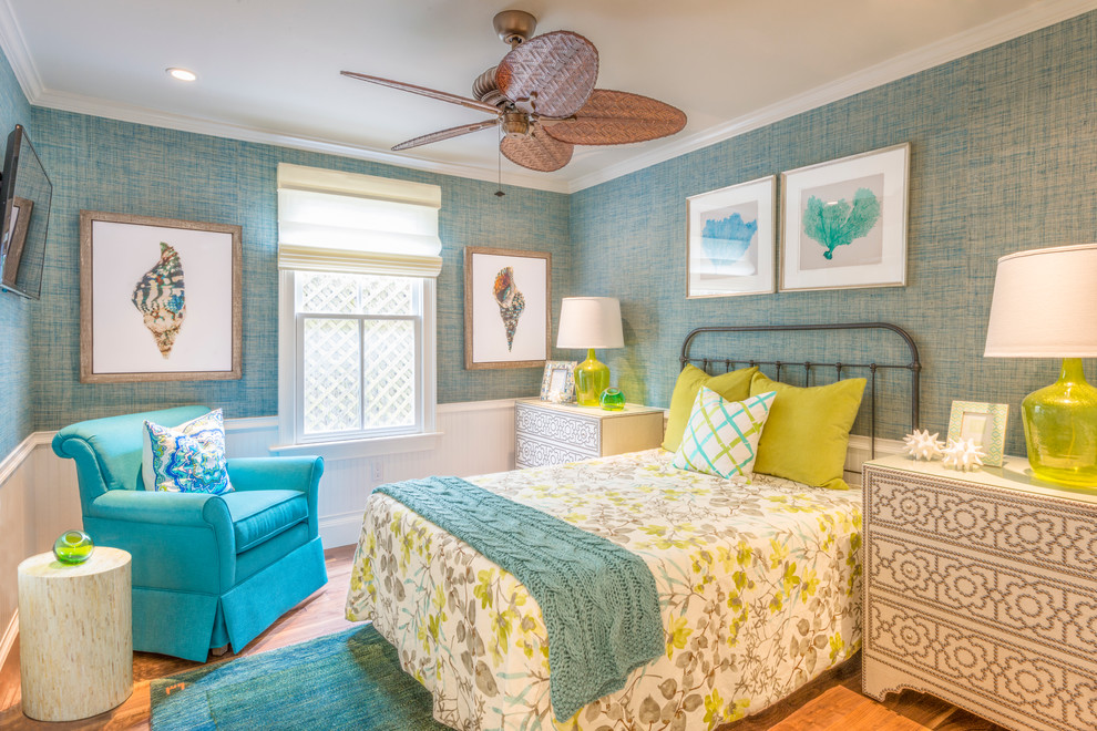 This is an example of a large tropical guest bedroom in Miami with blue walls, medium hardwood floors, no fireplace and beige floor.