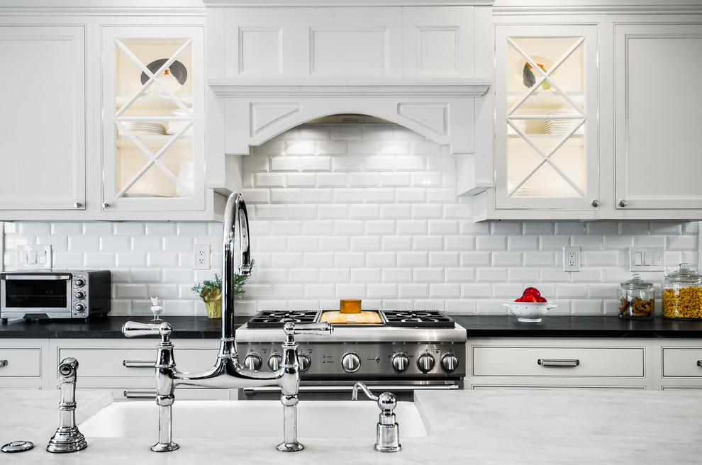 This is an example of a large traditional l-shaped eat-in kitchen in Philadelphia with a farmhouse sink, recessed-panel cabinets, white cabinets, soapstone benchtops, white splashback, subway tile splashback, stainless steel appliances, dark hardwood floors and with island.