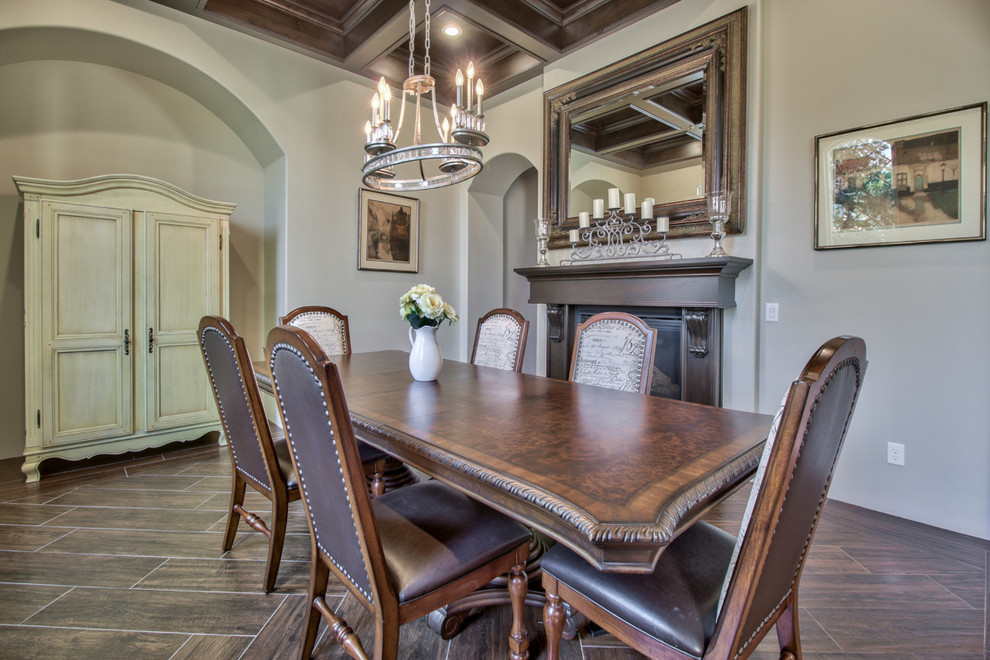 Inspiration for a large traditional separate dining room in Phoenix with grey walls, dark hardwood floors, a standard fireplace, brown floor and a wood fireplace surround.