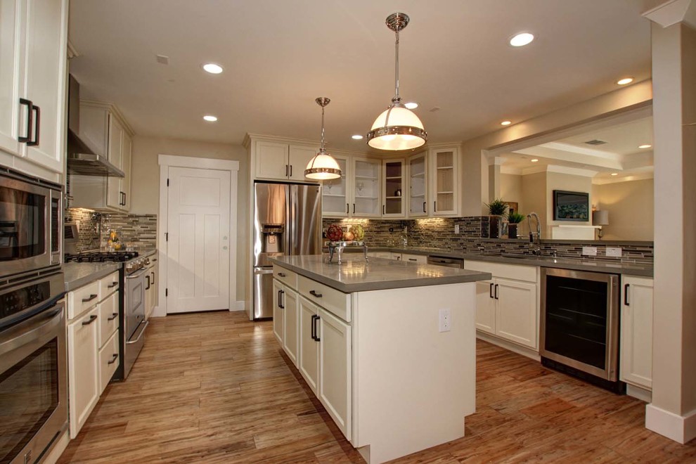 Large trendy galley light wood floor kitchen photo in Austin with an undermount sink, recessed-panel cabinets, white cabinets, quartzite countertops, multicolored backsplash, mosaic tile backsplash, stainless steel appliances and an island