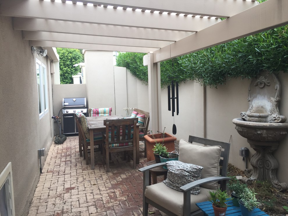 Small country backyard patio in Phoenix with a water feature, brick pavers and a pergola.