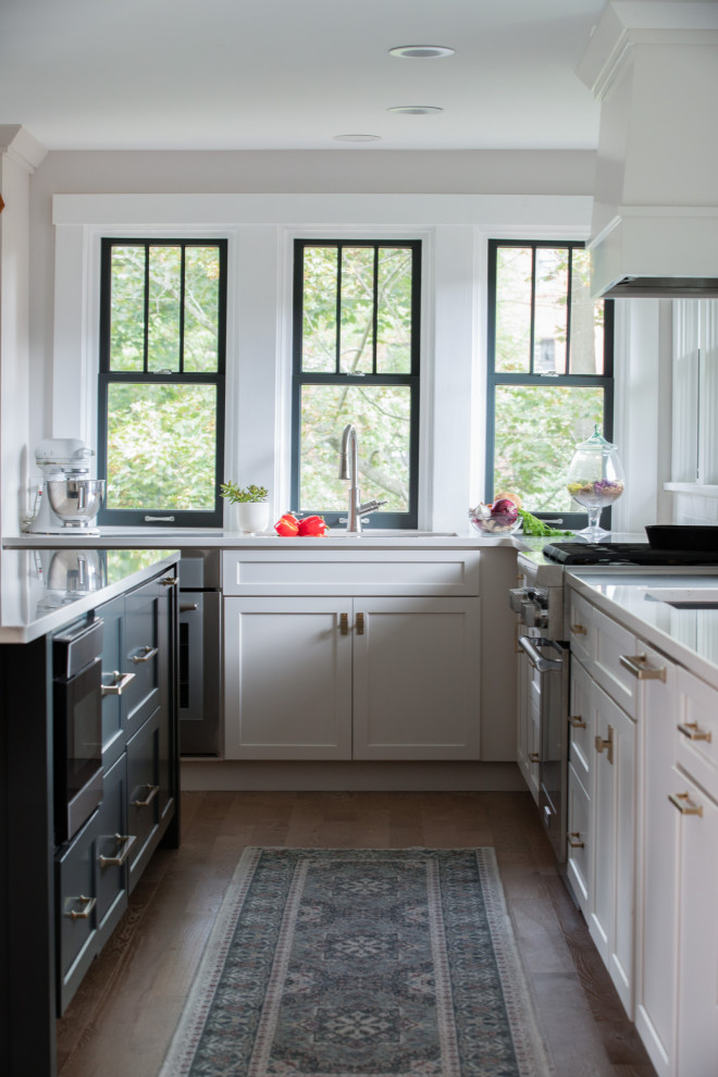 Inspiration for a transitional l-shaped medium tone wood floor and brown floor eat-in kitchen remodel with a drop-in sink, shaker cabinets, white cabinets, quartzite countertops, white backsplash, subway tile backsplash, stainless steel appliances, an island and green countertops