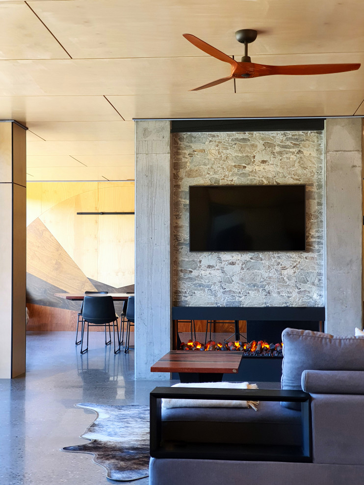 Inspiration for a large contemporary open concept living room in Wollongong with multi-coloured walls, concrete floors, a two-sided fireplace, a concrete fireplace surround, a wall-mounted tv, grey floor, timber and decorative wall panelling.