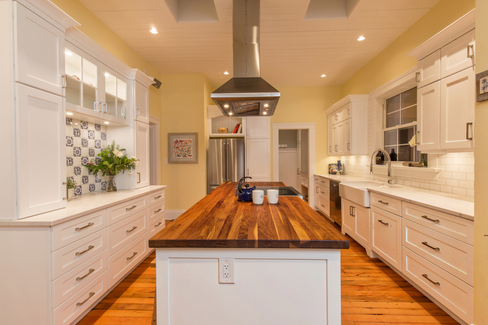 Inspiration for a large country galley kitchen pantry in Other with a farmhouse sink, shaker cabinets, white cabinets, wood benchtops, white splashback, mosaic tile splashback, stainless steel appliances, medium hardwood floors, with island and orange floor.
