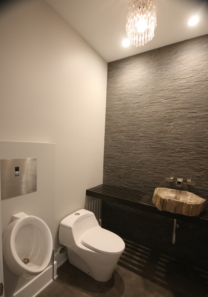 Photo of a contemporary powder room in Chicago with a one-piece toilet, stone tile, white walls, porcelain floors, wood benchtops, grey floor, a vessel sink and black benchtops.