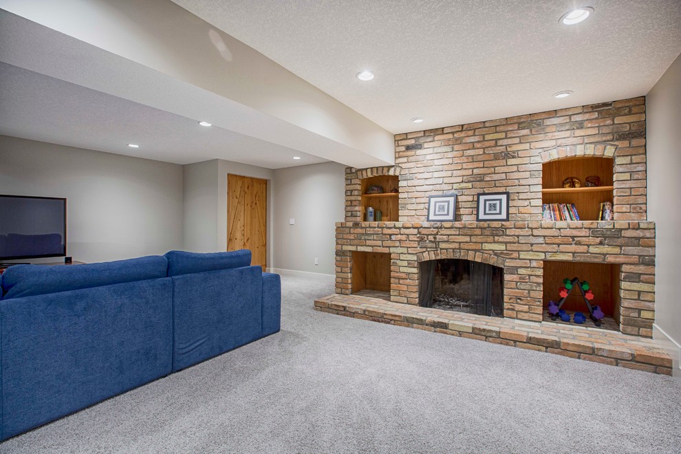 Inspiration for a large transitional look-out carpeted basement remodel in Calgary with beige walls, a standard fireplace and a brick fireplace