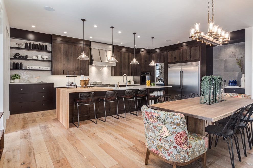 Design ideas for a large country single-wall eat-in kitchen in Calgary with a farmhouse sink, flat-panel cabinets, dark wood cabinets, quartz benchtops, white splashback, porcelain splashback, stainless steel appliances, light hardwood floors, with island and beige floor.