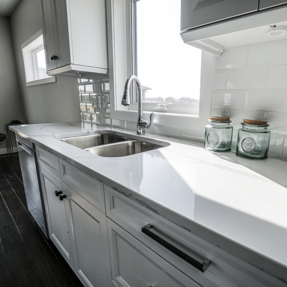 This is an example of a modern kitchen in Vancouver with a double-bowl sink, white cabinets, white splashback and white worktops.