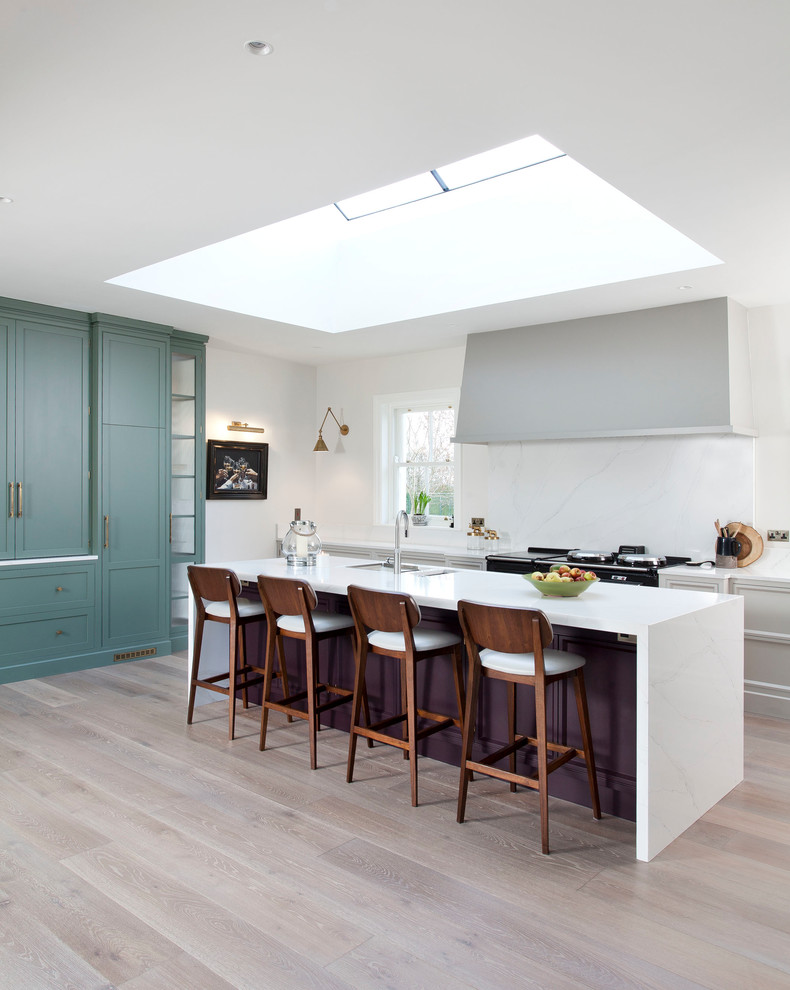 This is an example of a transitional l-shaped kitchen in Dublin with an undermount sink, recessed-panel cabinets, purple cabinets, white splashback, light hardwood floors, with island and beige floor.