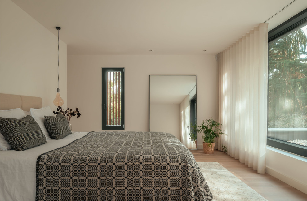 Diseño de dormitorio contemporáneo con paredes beige, suelo de madera clara y suelo beige