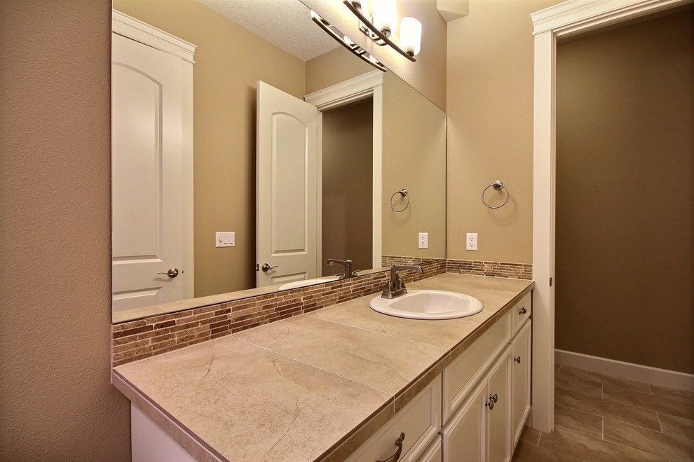 Large transitional master bathroom in Portland with recessed-panel cabinets, white cabinets, an alcove tub, a shower/bathtub combo, a two-piece toilet, beige tile, ceramic tile, beige walls, travertine floors, a drop-in sink and tile benchtops.