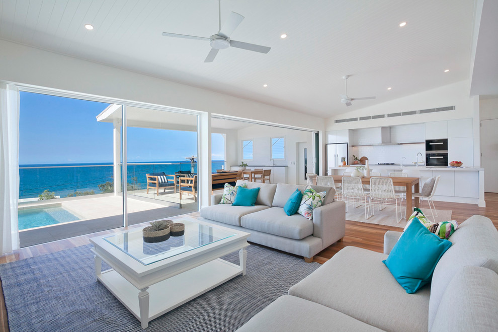 This is an example of a large beach style living room in Sunshine Coast with white walls and medium hardwood floors.