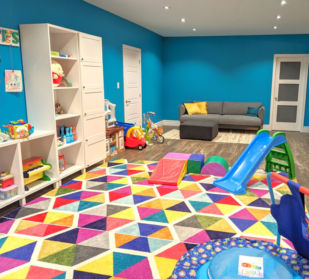 This is an example of a large contemporary gender neutral kids' bedroom in Montreal with blue walls, carpet and multi-coloured floors.
