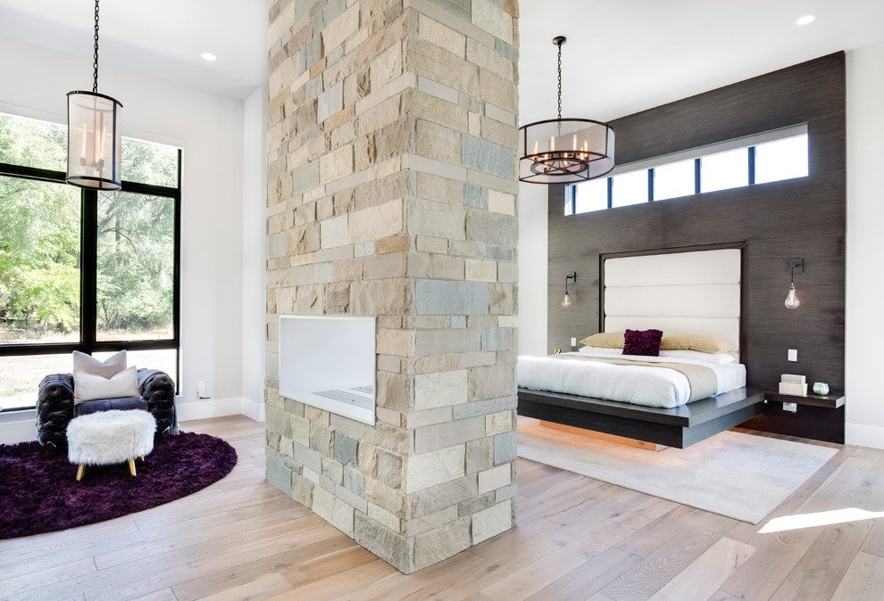 Inspiration for a contemporary master bedroom in Salt Lake City with grey walls, medium hardwood floors, a two-sided fireplace, a stone fireplace surround and brown floor.