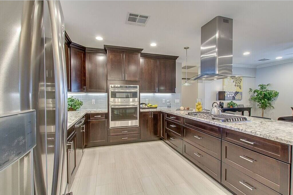 Example of a large transitional u-shaped porcelain tile and beige floor eat-in kitchen design in Phoenix with a double-bowl sink, dark wood cabinets, shaker cabinets, granite countertops, gray backsplash, glass tile backsplash, stainless steel appliances and a peninsula